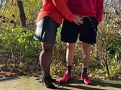 Mother-in-law assists with outdoor urination in public, wearing pantyhose and heels.