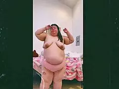 mature old cougar performs topless dance in front of webcam, showcasing natural saggy tits