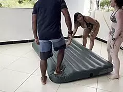 Two hotties inflate inflatable mattress with street man's help.