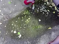 A milf pees outdoors behind garages.